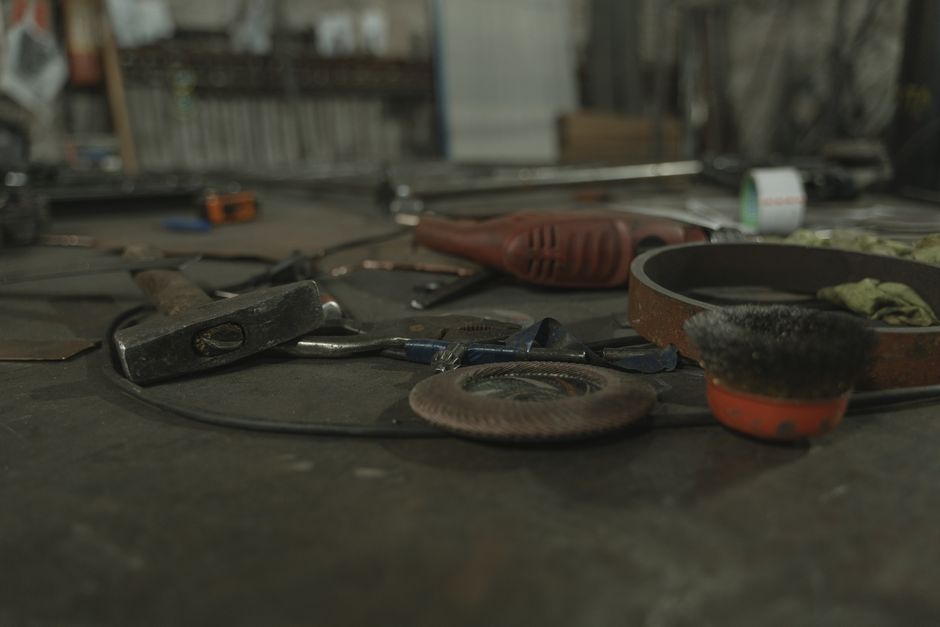 A selection of various tools scattered on a workbench in an industrial setting.